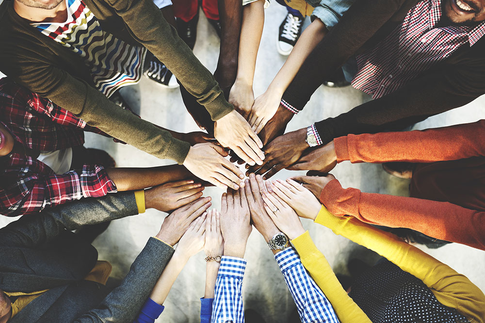 Circle of people bringing their hands together in the middle